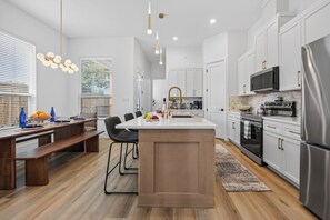 A modern kitchen with white cabinetry, stainless steel appliances, and a central island. - New Spacious Cowboys Retreat | Walk to AT&T Stadium (Arlington)