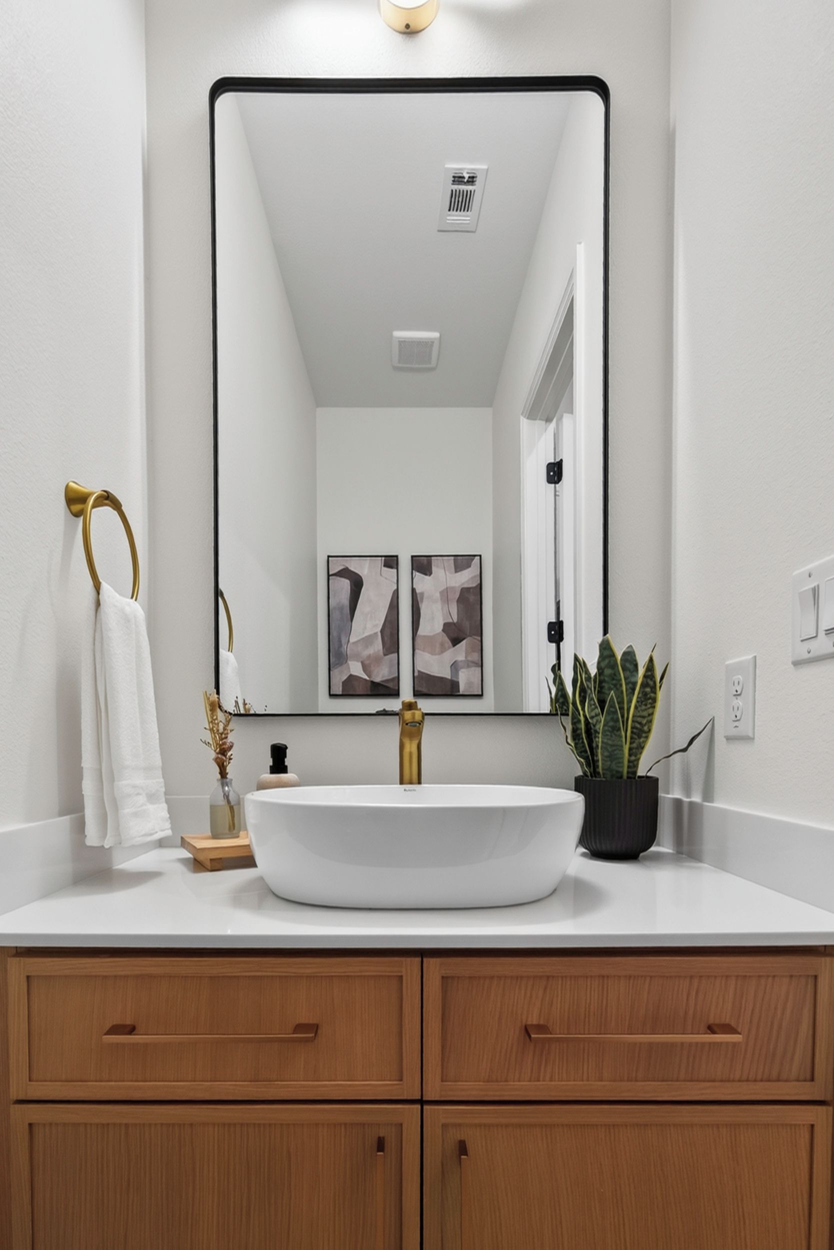 A bathroom with a white sink, gold fixtures, wooden cabinets, and a large mirror.