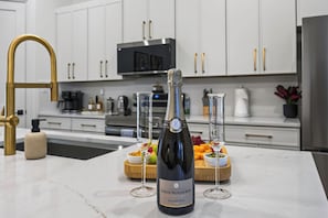 A kitchen with a marble countertop, a bottle of Louis Roederer champagne, and two glasses. - Prime Location | New Luxury House | Walk to AT&T (Arlington)