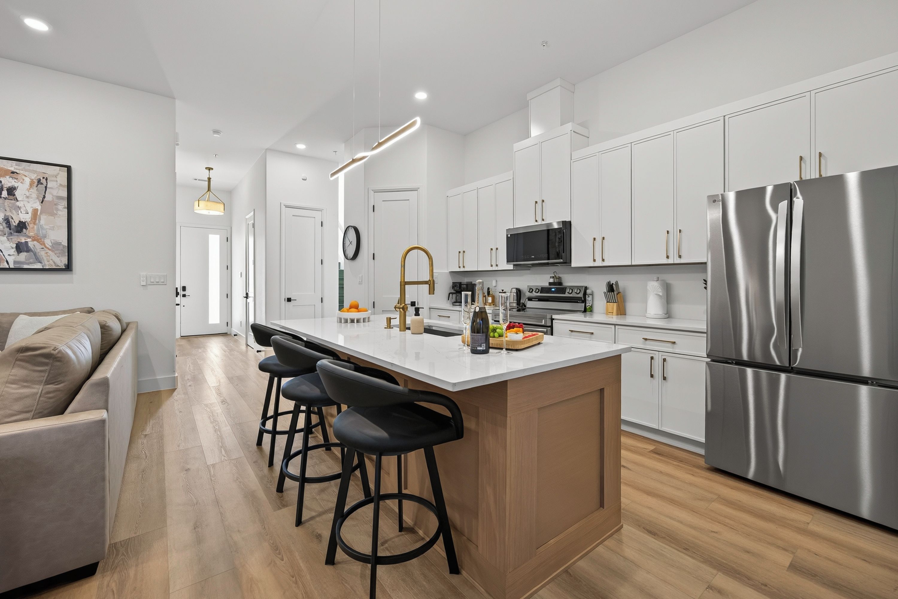 A modern kitchen with white cabinets, stainless steel appliances, and a bar area with stools.