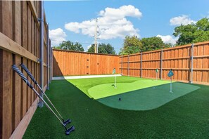 A backyard with artificial turf, a putting green, and a wooden fence. - Prime Location | New Luxury House | Walk to AT&T (Arlington)