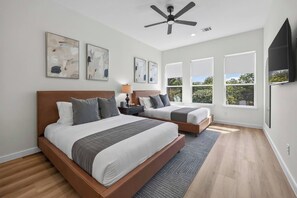 A bedroom with two beds, a ceiling fan, artwork on the walls, and large windows. - Prime Location | New Luxury House | Walk to AT&T (Arlington)