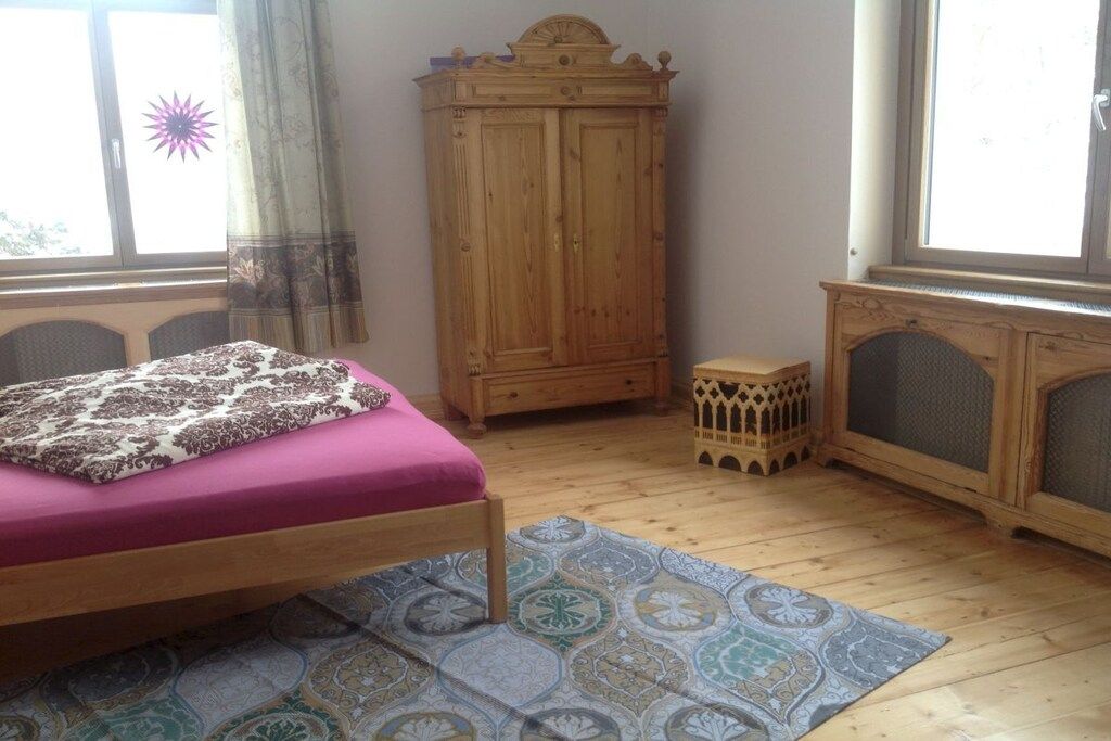 Ein Schlafzimmer mit einem Bett, einem Holzschrank, einer kleinen Kommode und einem gemusterten Teppich.