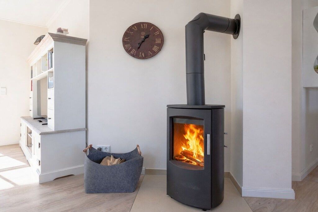 A modern living room with a wood-burning stove, a clock, and a bookshelf.
