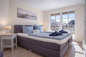 A bedroom with a large bed, two bedside tables, a window with a view, and a painting on the wall. - Holiday home with 3 bedrooms (Fuhlendorf)