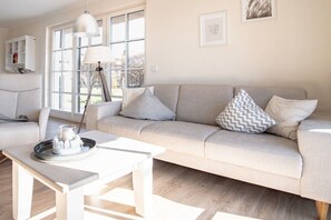 A modern living room with a sofa, a coffee table, and a lamp. - Holiday home with 3 bedrooms (Fuhlendorf)