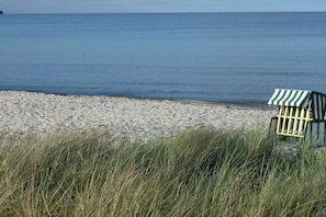 A beach with a striped beach chair and grass in the foreground. - Holiday apartment with 2 bedrooms (Breege\/Juliusruh OT Juliusruh)