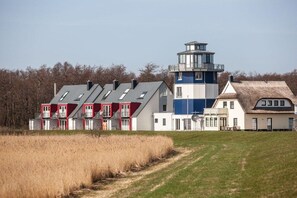 A coastal building with multiple levels, a prominent tower, and a thatched-roof structure. - Holiday home in Breege with swimming pool (Breege)