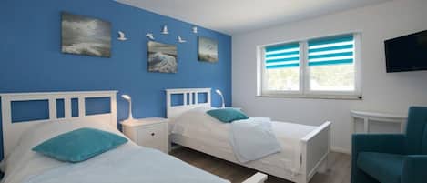 Una habitación con dos camas, un televisor y obras de arte en la pared.