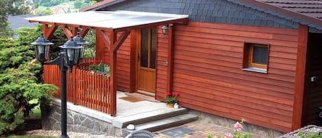 A wooden cabin with a porch, a table, and chairs outside.
