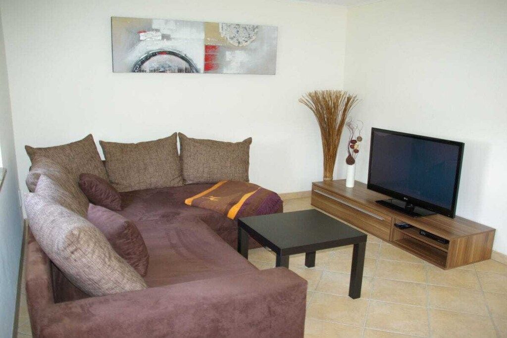 A living room with a sofa, a coffee table, a flat-screen TV, and a decorative vase.