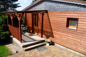 Ein Holzhaus mit einer Veranda, einer Tür und einem Fenster.