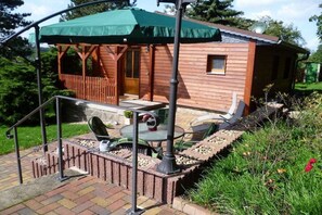 A wooden cabin with a patio area, a covered seating area, and a small deck. - Holiday home with 1 bedroom (Diera-Zehren \/ OT Nieschütz)
