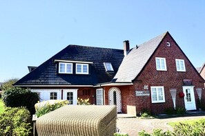 A two-story building with a brick facade, a black roof, and a sign indicating it is a hotel. - Holiday apartment with 1 bedroom (Wenningstedt-Braderup)
