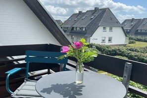 Ein Balkon mit rundem Tisch, einem Stuhl und einer Blumenvase.