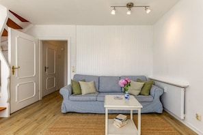 Ein Zimmer mit einem gestreiften Sofa, einem kleinen weißen Tisch und einer Tür zu einem anderen Raum.