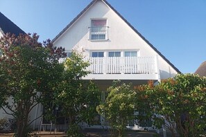 A two-story house with a white exterior, a balcony, and a picket fence. - Holiday apartment in Breege with Wi-Fi (Breege)