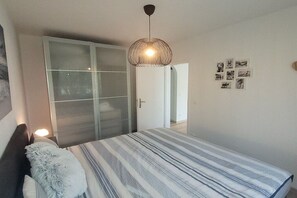 A bedroom with a bed, a wardrobe, a hanging light fixture, and wall-mounted pictures. - Holiday apartment in Breege with Wi-Fi (Breege)