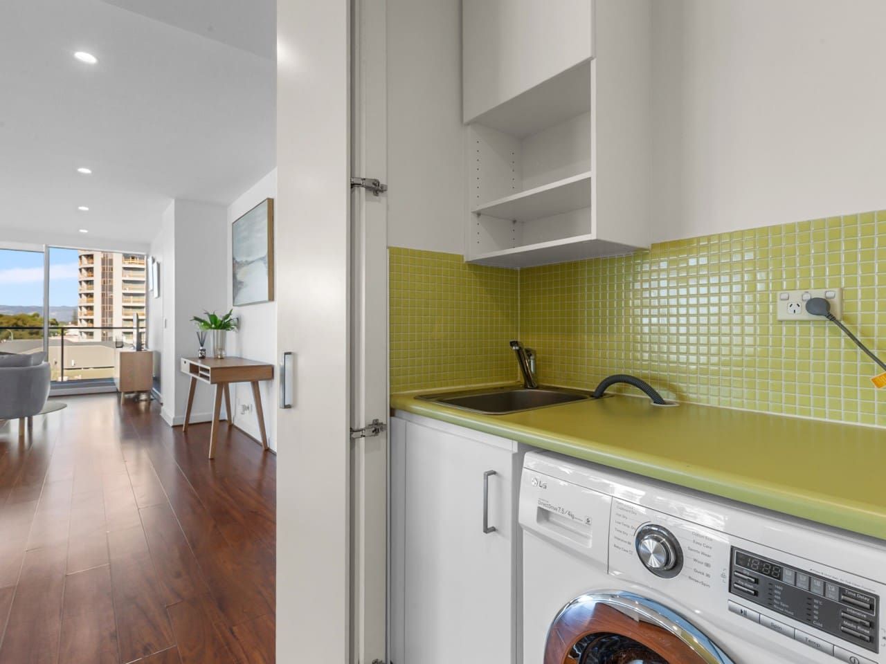 A modern kitchen with a washing machine, a sink, and a dining area with a view.