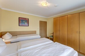 A hotel room with two beds, a wardrobe, and a door. - At Schloonsee, Apartment C-2 (Seebad Heringsdorf)