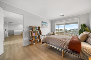 Ein Schlafzimmer mit einem Bett, einem Bücherregal und Blick ins Freie.