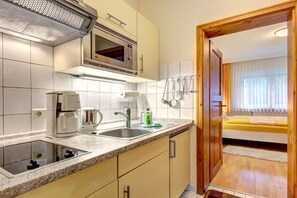 A compact kitchen with a microwave, coffee maker, and sink. - House by the Forest Apartment 3 (Seebad Ahlbeck)