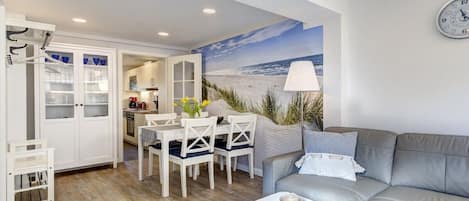 Un espacio habitable moderno con comedor, sofá y cocina al fondo.
