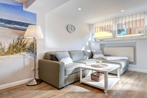 A modern living room with a sofa, a lamp, and a view of the beach. - Richard House Apt. 3 (Seebad Ahlbeck)