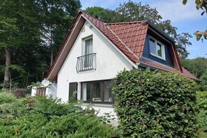 Ein Haus mit schrägem Dach, einem Balkon und einem Fenster.
