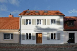 A two-story building with a white facade, multiple windows with shutters, and a red-tiled roof. - Holiday home in Barth with swimming pool (Barth)
