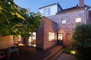 A brick house with a wooden deck and a door leading to a covered patio. - Holiday home in Barth with swimming pool (Barth)