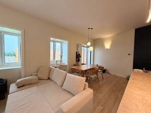 A modern living room with a sofa, dining table, and chairs. There is a window providing natural light and a view of the outdoors. - One-bedroom apartment with a large terrace near Avenida da Liberdade (Lisboa)