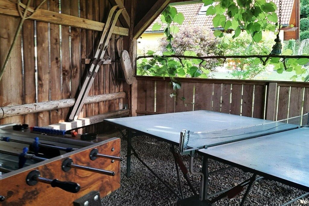 An outdoor table tennis table with a wooden fence in the background.
