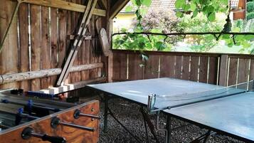 An outdoor table tennis table with a wooden fence in the background.