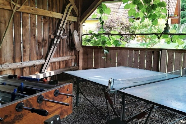 An outdoor table tennis table with a wooden fence in the background.
