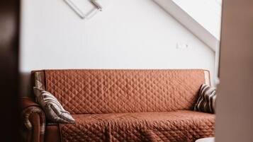 A room with a brown leather sofa, a small round table, and a patterned rug.