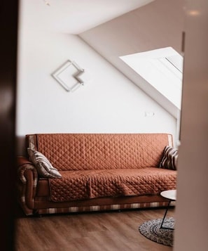 A room with a brown leather sofa, a small round table, and a patterned rug.