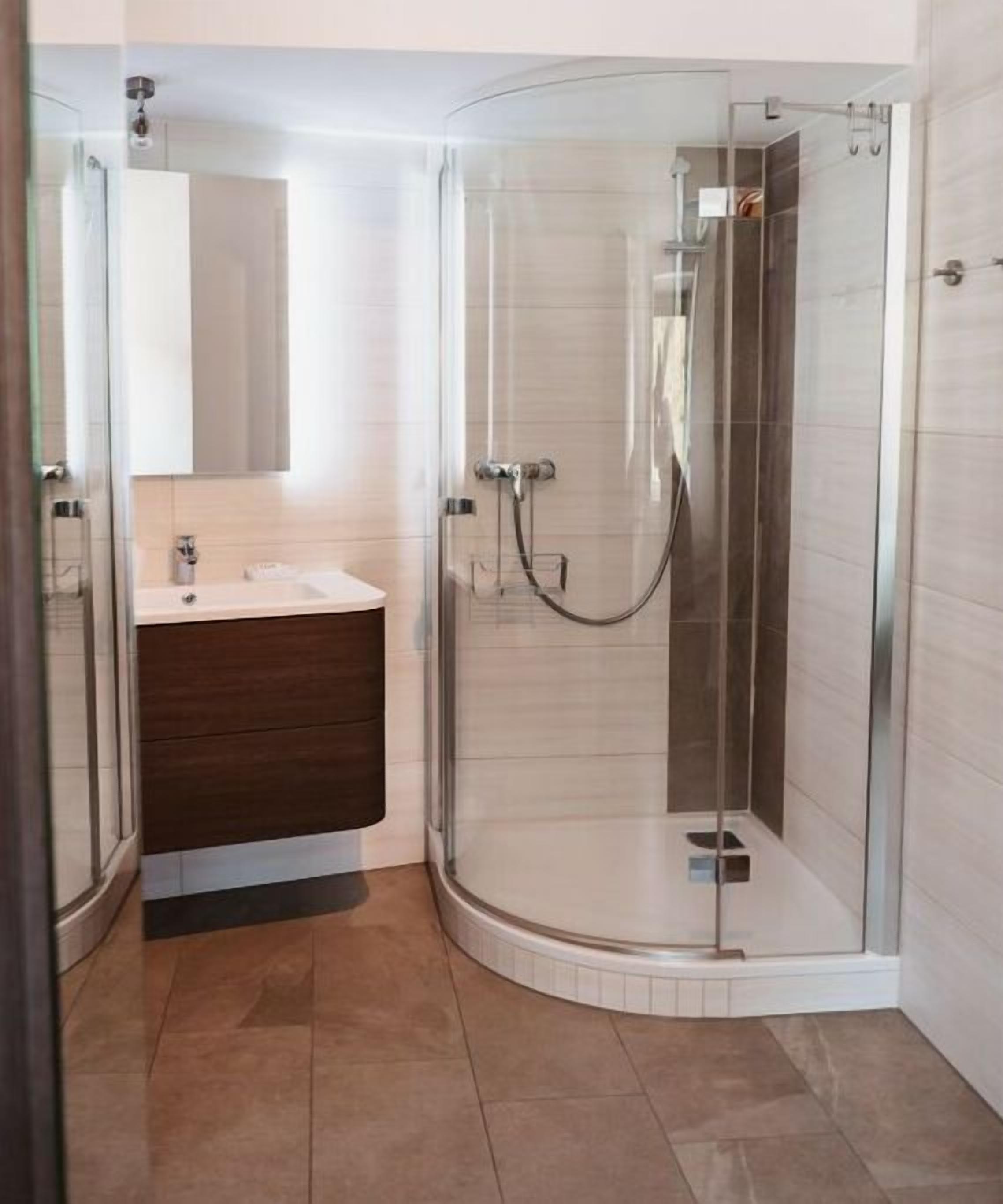 A modern bathroom with a glass-enclosed shower, a white sink, and a dark-toned vanity.
