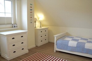 A bedroom with a bed, a dresser, a nightstand, and a window. - Holiday home in Breege with swimming pool (Breege)