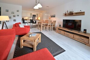 Ett modernt vardagsrum med en röd soffa, ett soffbord i trä och en tv som står på ett träställ.
