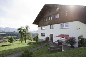A two-story house with a balcony, a garden with a bench, and a view of the countryside. - Holiday home in Doren with swimming pool (Doren)