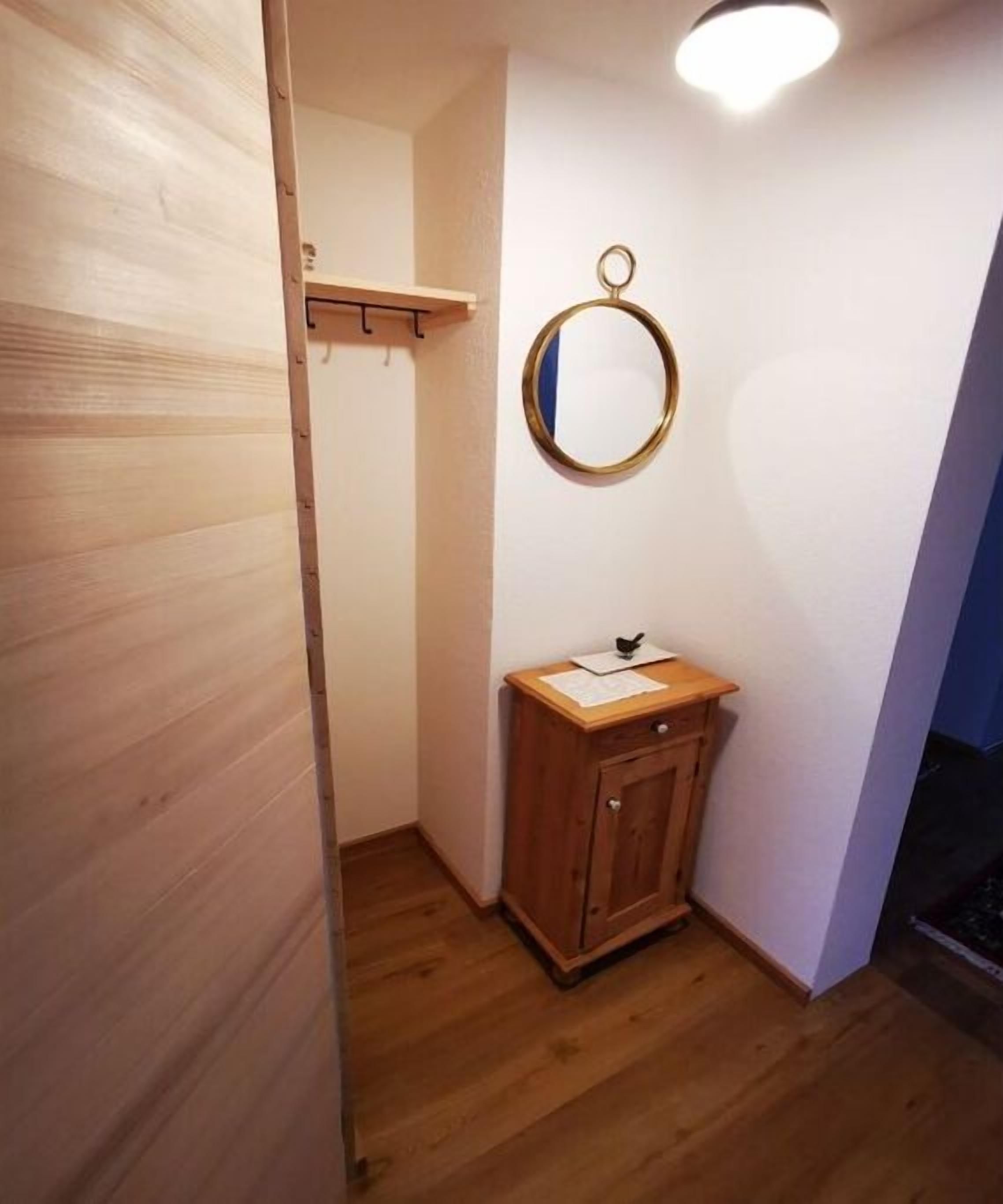 A small bathroom with a wooden cabinet, a mirror, and a shelf.