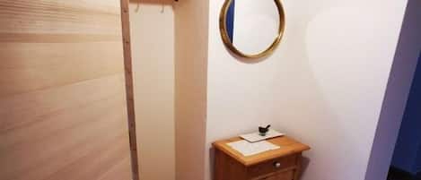 A small bathroom with a wooden cabinet, a mirror, and a shelf.
