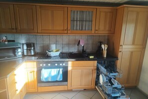 Una cocina con armarios de madera, horno de acero inoxidable, lavavajillas y un lavamanos.