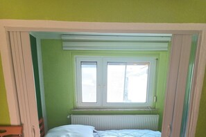 Una habitación con ventana, radiador y cama.