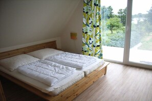 A bedroom with a wooden bed frame, white bedding, and a view of greenery through a window. - Holiday home in Jabel with swimming pool (Jabel)
