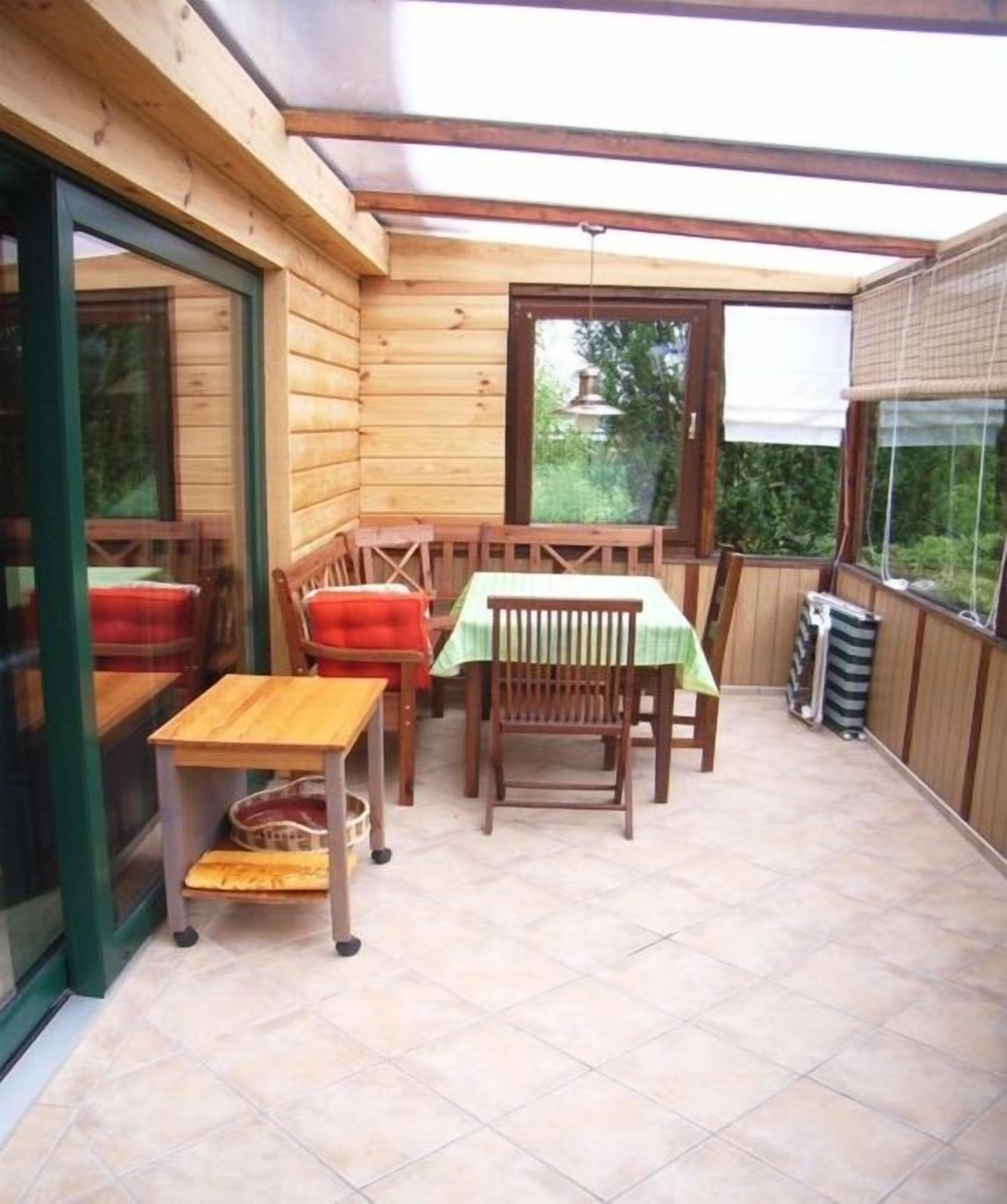A wooden-paneled room with a table and chairs, a small table with a basket, and a window with a view of greenery.
