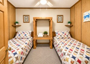 Ein Schlafzimmer mit zwei Betten, einer Holzbank und einem Deckenventilator.