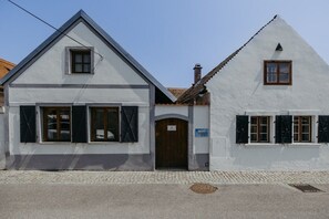 A two-story building with a gabled roof, a wooden door, and a small window on the upper floor. - Streckhof Stiefelgasse attic (Purbach am Neusiedler See)