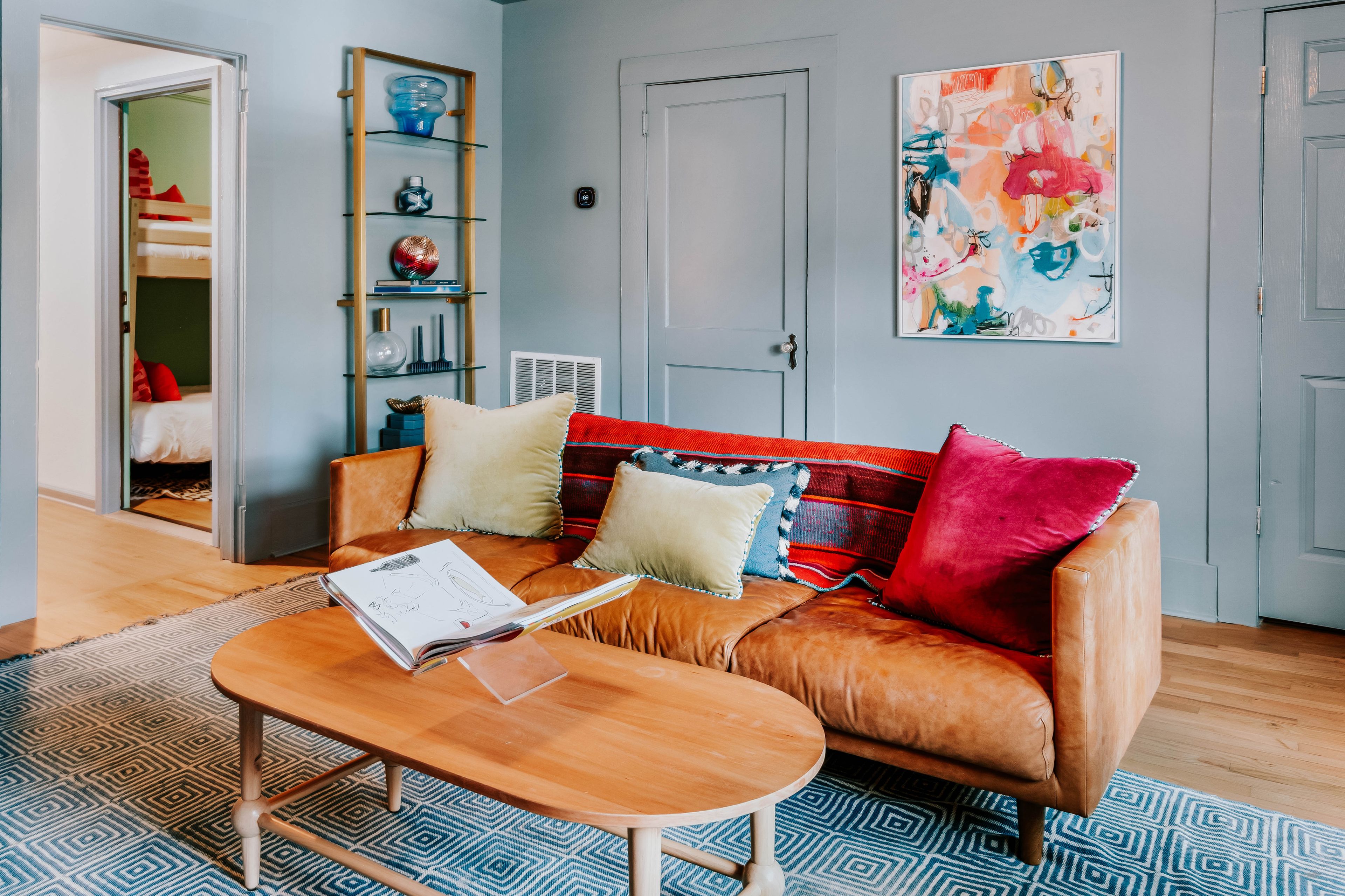 A living room with a brown leather sofa, a wooden coffee table, and a patterned rug.
